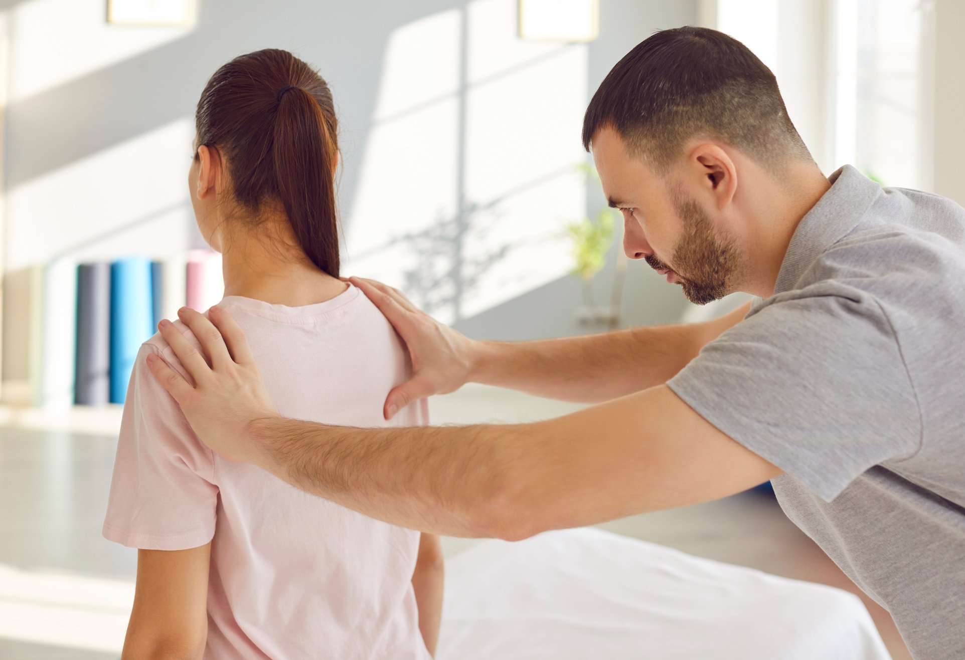 Focused rehabilitation therapist works with patient performing physical assessment of her shoulder.