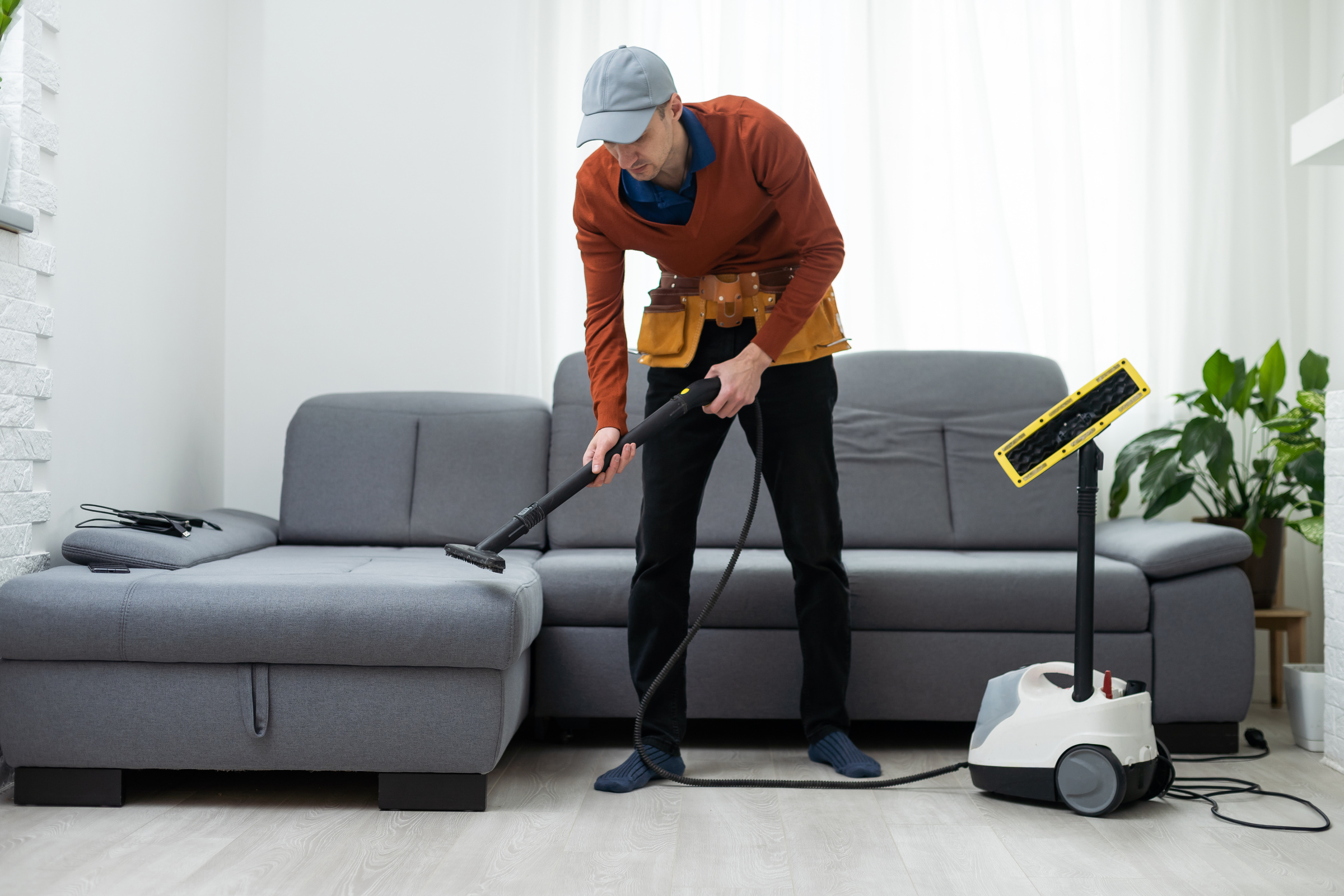 Dry cleaning worker removing dirt from sofa indoors